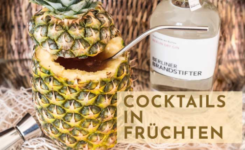 Ananas mit Strohhalm, Gin-Flasche, Cocktails in Früchten