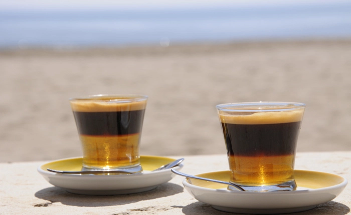 Zwei Gläser mit Licor 43 und Kaffee am Strand